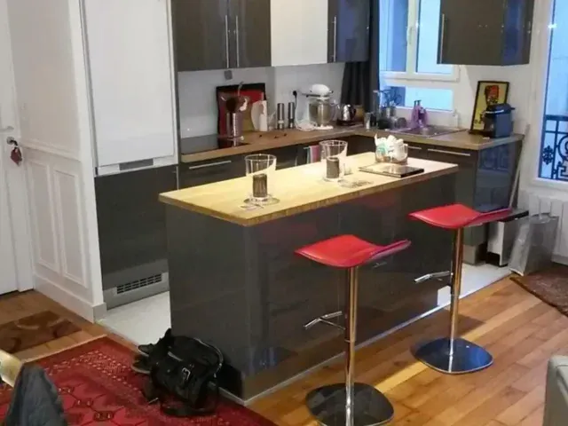 Aménagement cuisine sur-mesure gris laqué, îlot central et plan de travail bois.